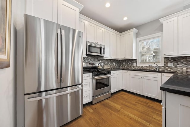 kitchen with appliances with stainless steel finishes, dark wood-type flooring, white cabinetry, and backsplash