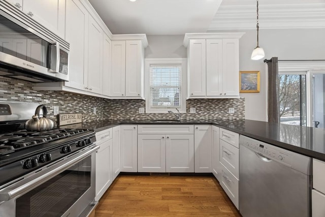 kitchen with decorative light fixtures, white cabinetry, light hardwood / wood-style flooring, decorative backsplash, and appliances with stainless steel finishes