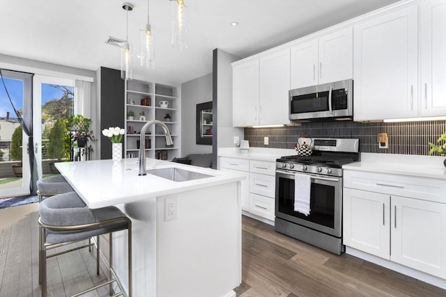 kitchen with appliances with stainless steel finishes, a sink, backsplash, white cabinets, and light countertops
