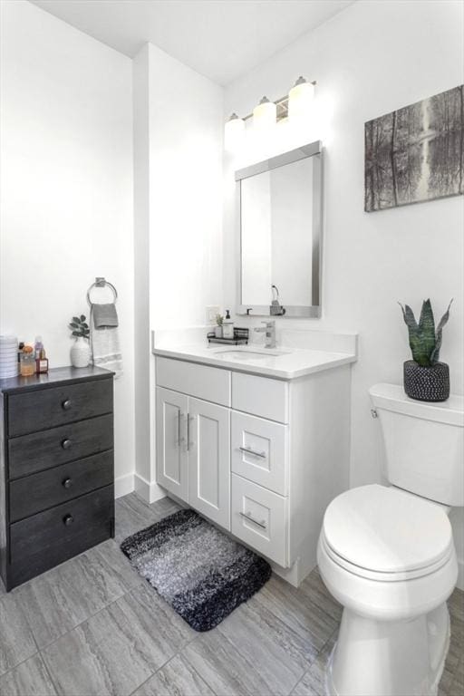 bathroom featuring toilet, vanity, and baseboards