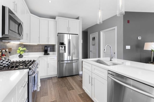kitchen with stainless steel appliances, a sink, wood finished floors, light countertops, and white cabinetry
