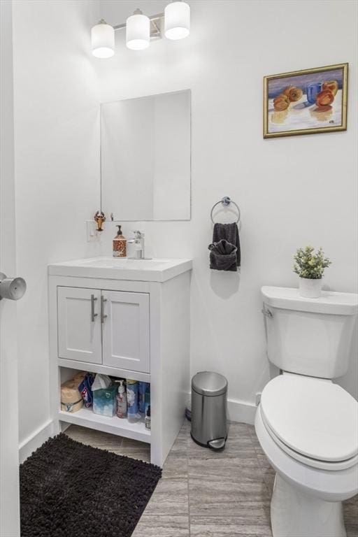 bathroom with baseboards, toilet, and vanity