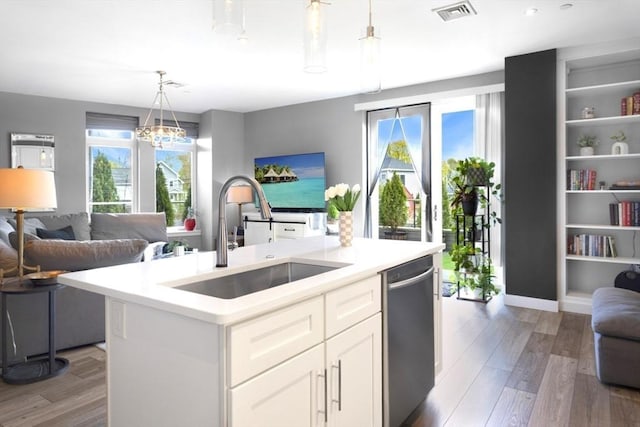 kitchen with open floor plan, a sink, stainless steel dishwasher, light countertops, and light wood-type flooring