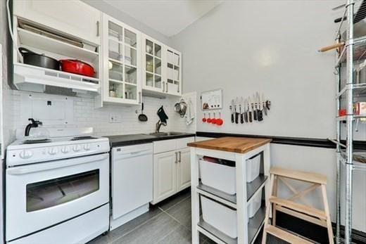 kitchen with a sink, wood counters, under cabinet range hood, backsplash, and white appliances