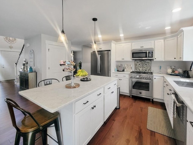 391 Gibbs St, Fall River, MA 02720 - kitchen with appliances with stainless steel finishes, light stone counters, white cabinetry, a breakfast bar, and recessed lighting