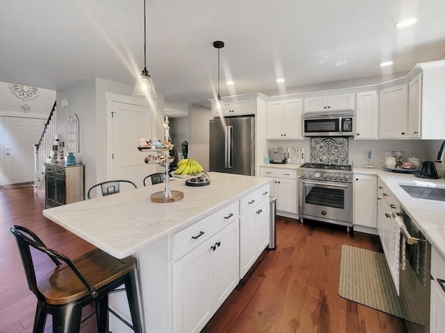 391 Gibbs St, Fall River, MA 02720 - kitchen featuring appliances with stainless steel finishes, a kitchen bar, white cabinets, light stone countertops, and recessed lighting