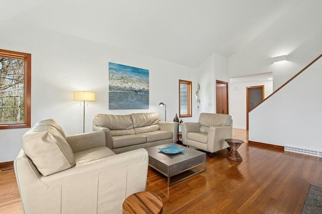 living room with plenty of natural light, lofted ceiling, wood finished floors, and baseboards
