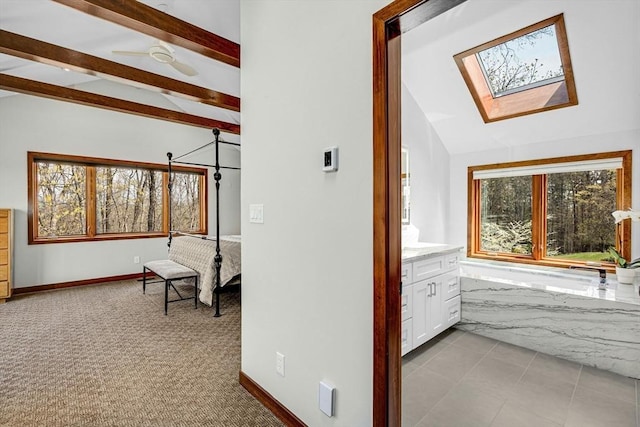 hallway with baseboards, lofted ceiling with skylight, and carpet