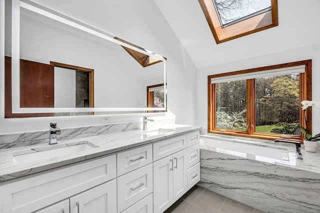 bathroom with a tub with marble appearance, double vanity, a sink, and vaulted ceiling with skylight