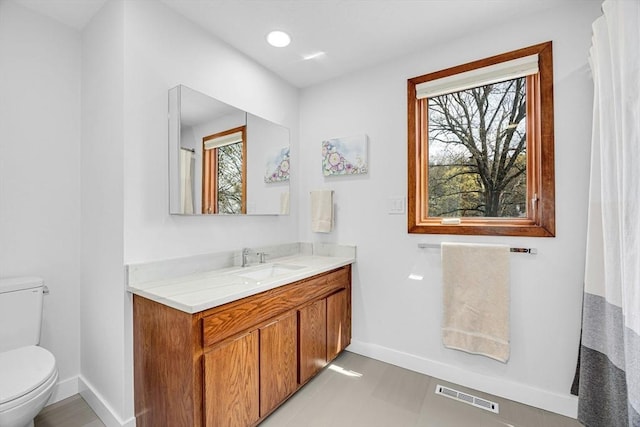 bathroom with a wealth of natural light, visible vents, toilet, and baseboards