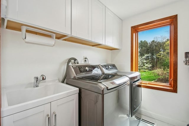 laundry room with baseboards, cabinet space, washer and clothes dryer, and a sink