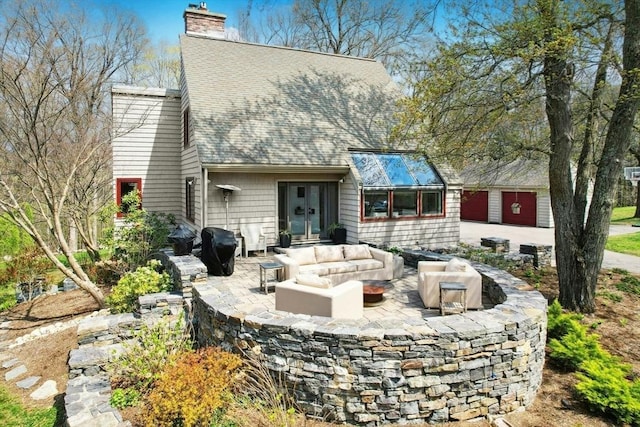back of property with a patio, an outdoor living space, a chimney, and roof with shingles