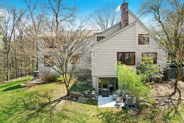 rear view of property with a chimney, a patio, cooling unit, and a yard