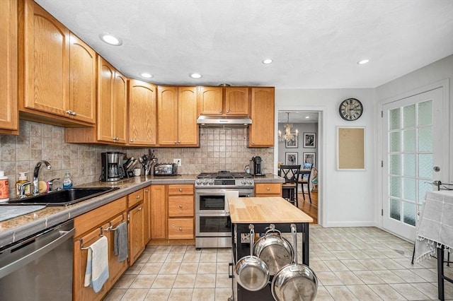 kitchen with stainless steel appliances, a sink, under cabinet range hood, backsplash, and recessed lighting