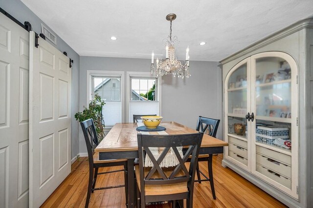 dining area featuring a barn door, a chandelier, light wood finished floors, and recessed lighting