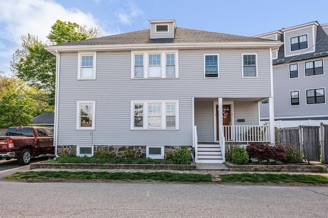 american foursquare style home with a porch and fence