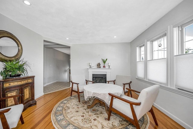 sitting room with baseboards, light wood-style floors, a glass covered fireplace, and recessed lighting