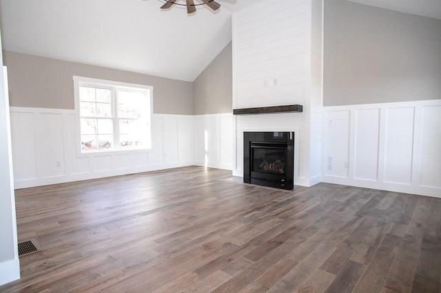 unfurnished living room featuring dark hardwood / wood-style floors, ceiling fan, a fireplace, and vaulted ceiling