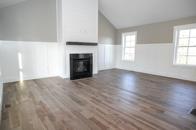 unfurnished living room with a large fireplace, wood-type flooring, and lofted ceiling