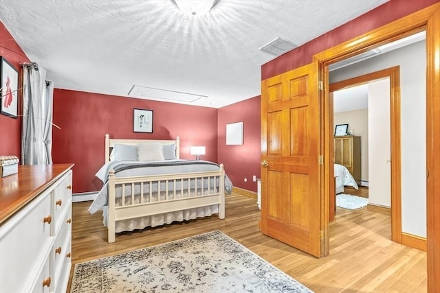 18 Sumac St, Billerica, MA 01821 - bedroom featuring attic access, light wood-style floors, baseboards, and a baseboard heating unit