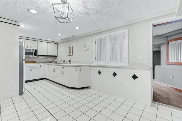 18 Sumac St, Billerica, MA 01821 - kitchen featuring appliances with stainless steel finishes, light countertops, tile walls, white cabinetry, and a textured ceiling