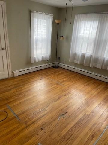 unfurnished room featuring a baseboard radiator and wood finished floors