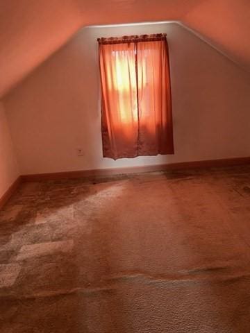 bonus room featuring lofted ceiling, carpet flooring, and baseboards