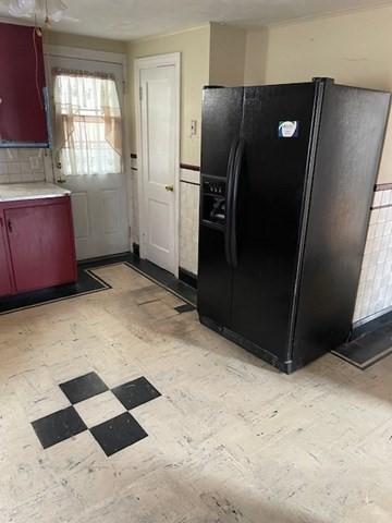 kitchen featuring light floors, black fridge, and light countertops