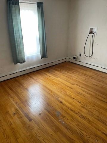 unfurnished room featuring baseboard heating and wood finished floors