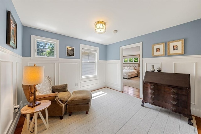 sitting room featuring wainscoting, wood finished floors, and a decorative wall