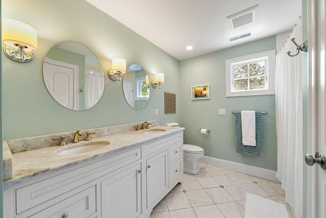 bathroom featuring toilet, baseboards, and double vanity