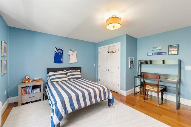 bedroom featuring wood finished floors, baseboards, and a closet