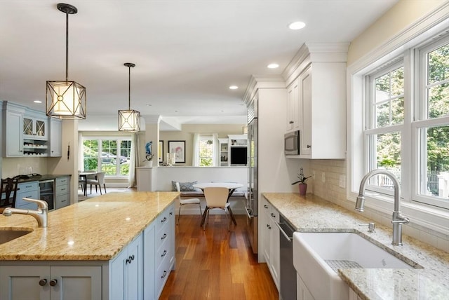 kitchen with a sink, stainless steel appliances, hanging light fixtures, dark wood-style floors, and recessed lighting