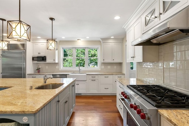 kitchen with high quality appliances, a sink, under cabinet range hood, white cabinetry, and recessed lighting