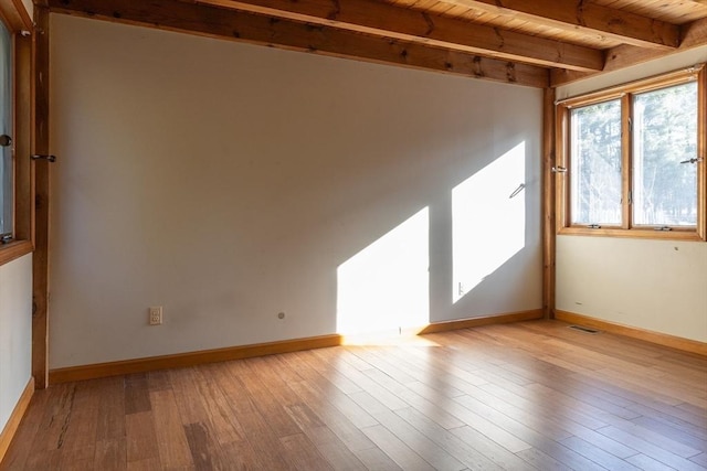 spare room featuring baseboards, visible vents, wooden ceiling, beamed ceiling, and light wood-type flooring