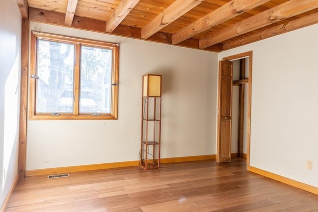 empty room with beam ceiling, wood finished floors, baseboards, and wooden ceiling