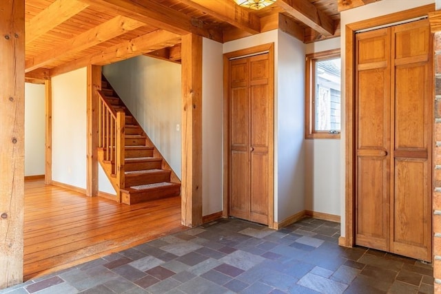 interior space with stairway, baseboards, beam ceiling, stone tile flooring, and wood ceiling