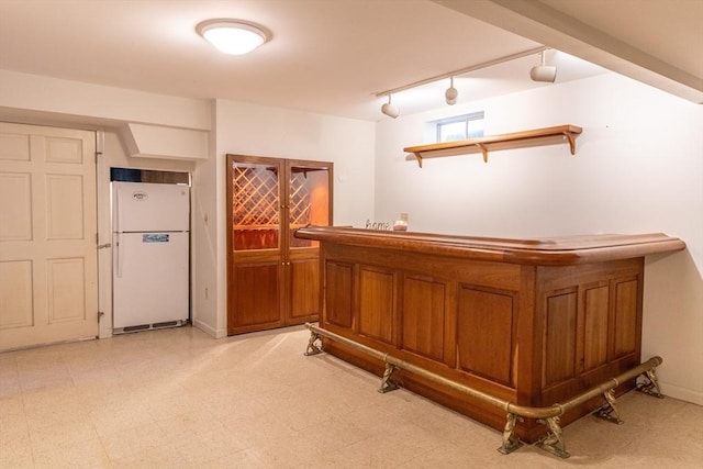 bar with a bar, light floors, track lighting, and freestanding refrigerator