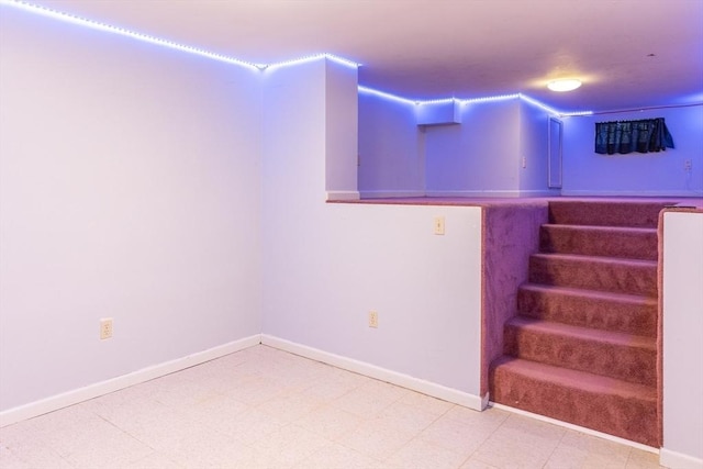 finished basement with tile patterned floors, stairway, and baseboards