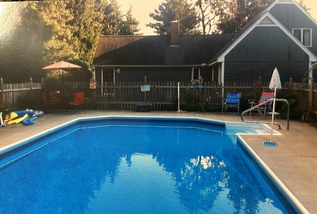 pool at dusk featuring a fenced in pool, a patio, and fence