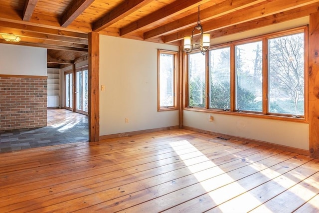 empty room with a chandelier, beamed ceiling, wood ceiling, and hardwood / wood-style floors