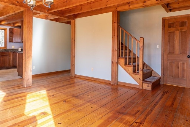 unfurnished living room featuring light wood-type flooring, stairway, and baseboards