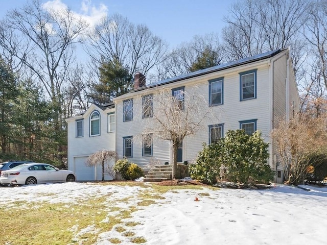 colonial house featuring a garage and a chimney