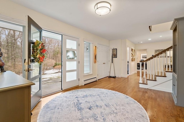 entrance foyer featuring baseboards, stairway, light wood-type flooring, a baseboard heating unit, and recessed lighting