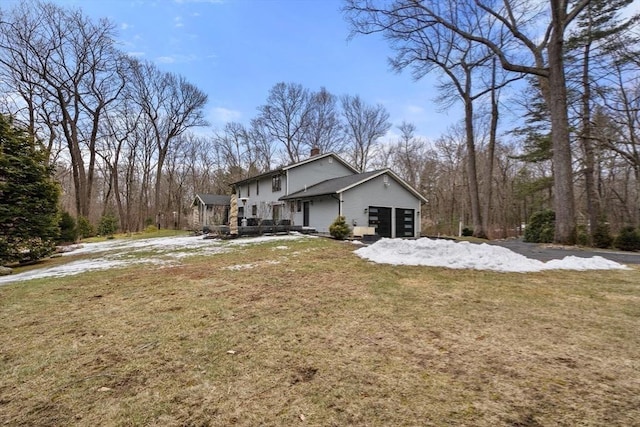 view of side of property featuring a garage, a chimney, and a lawn