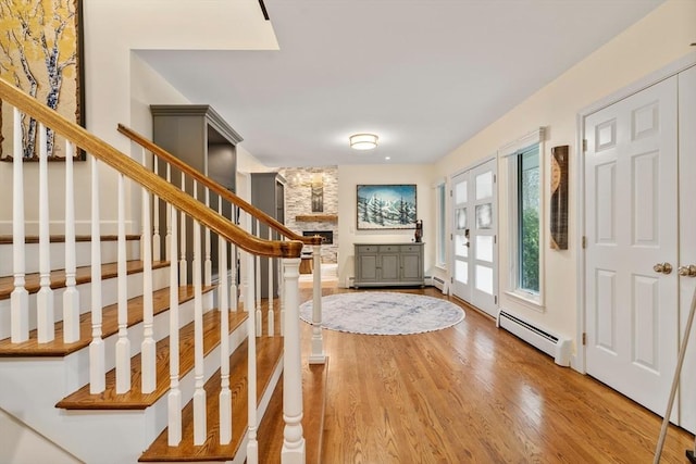 foyer with stairs, a baseboard heating unit, wood finished floors, and french doors