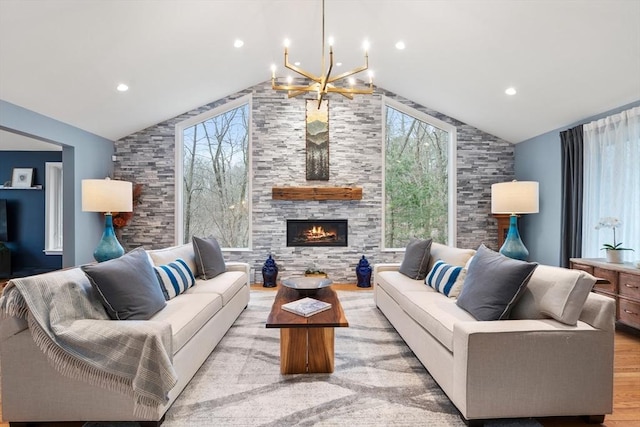 living area featuring light wood finished floors, plenty of natural light, a fireplace, and vaulted ceiling