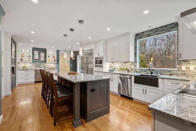 kitchen featuring a center island, white cabinets, a sink, and built in appliances