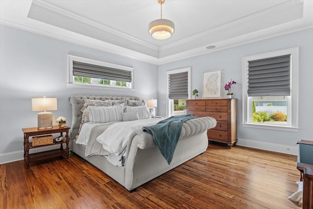 bedroom with a raised ceiling, crown molding, and hardwood / wood-style flooring