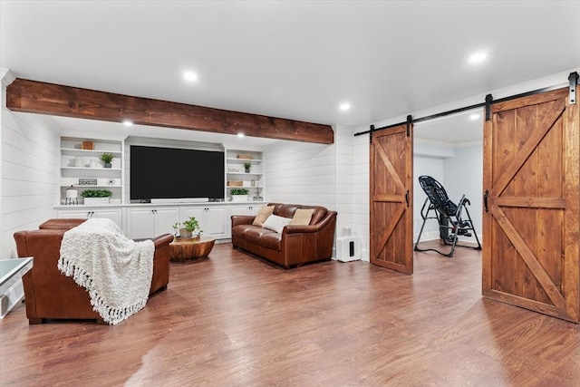 living room with beam ceiling, wood-type flooring, built in features, and a barn door